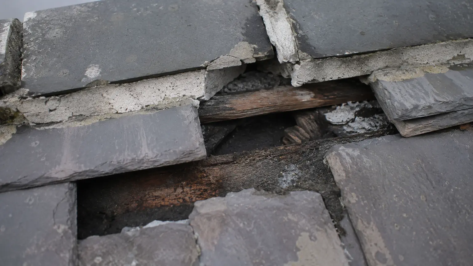 Close-up of slipped and cracked slates causing a roof leak in Ireland